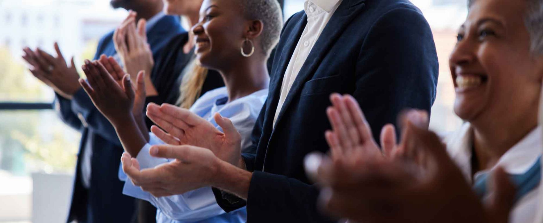 group of smiling businesspeople clapping after a presentation