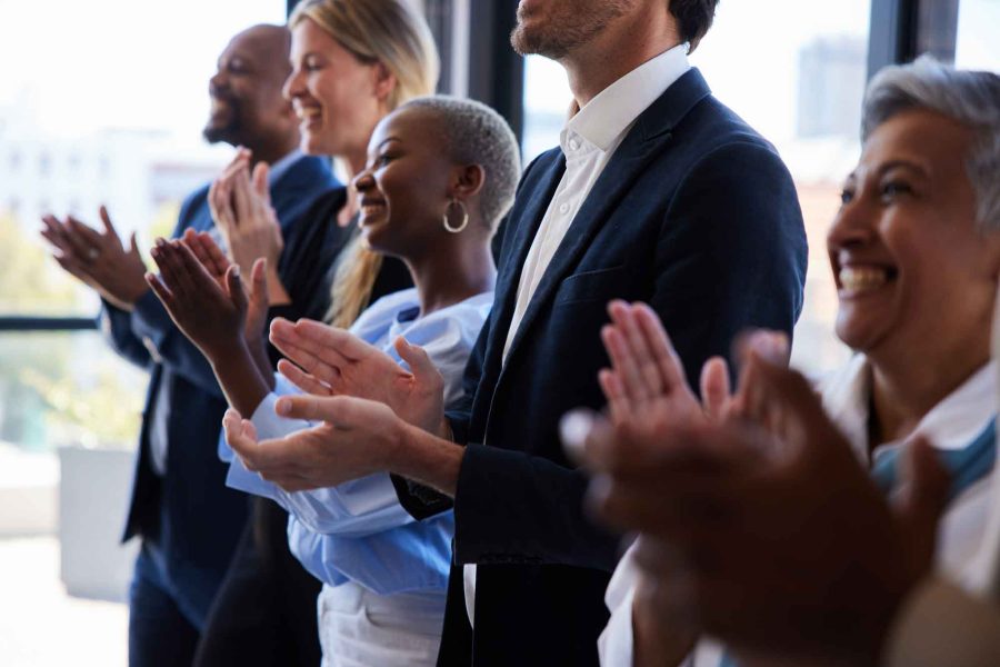 group of smiling businesspeople clapping after a presentation