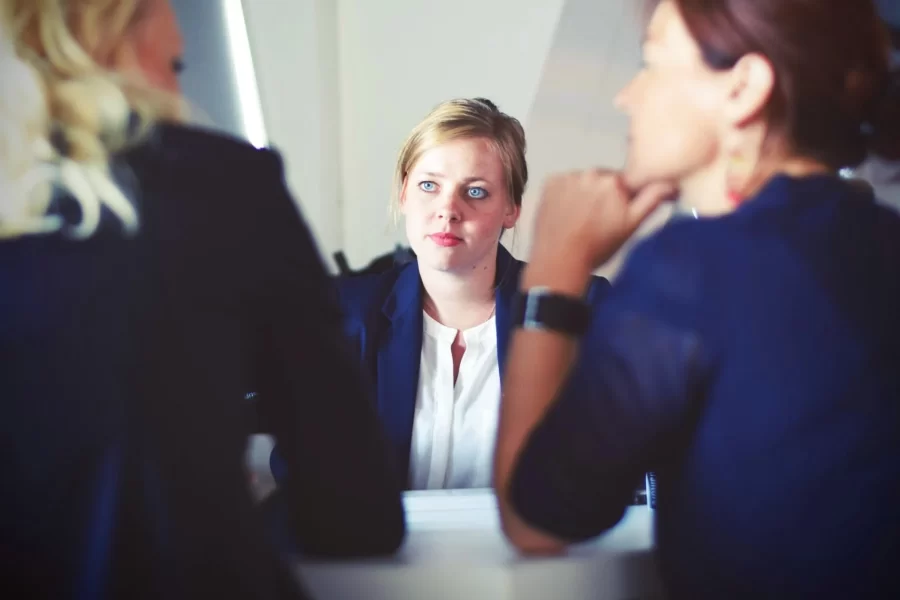 A woman engaged in conversation with two others at a table