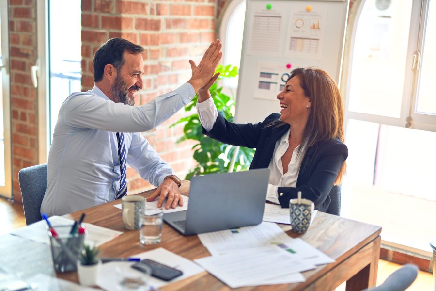Two professionals celebrate success with a high five at a desk
