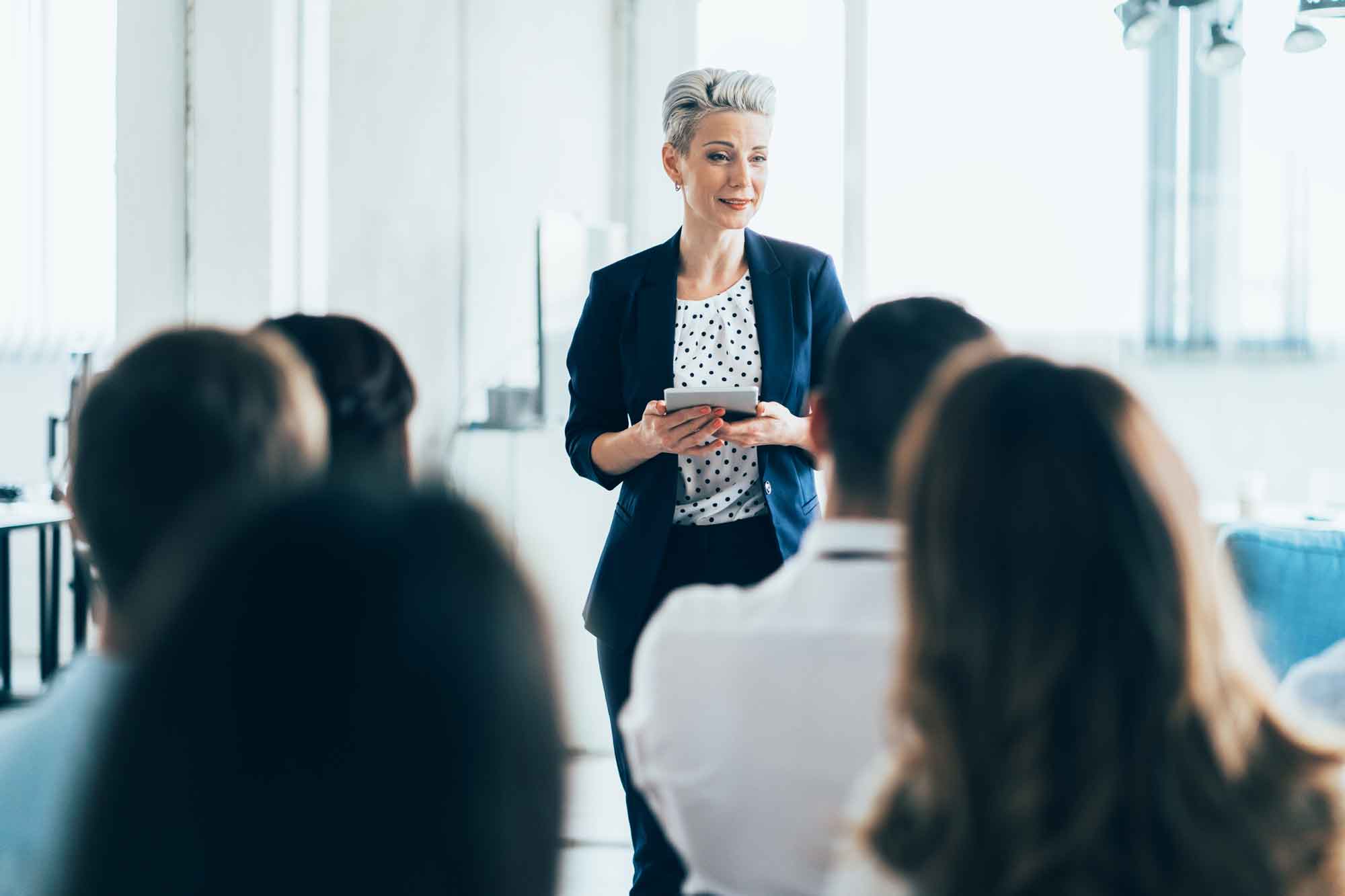 Business people attending a seminar in board room, speaker in front