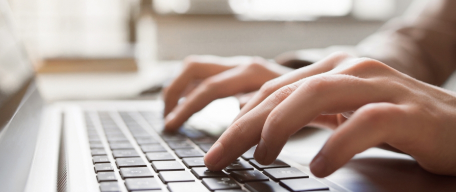 hands typing on a laptop keyboard