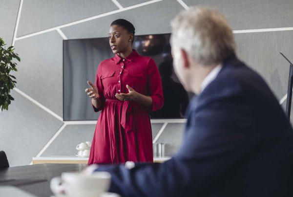 executive standing at head of conference table communicating pitch to colleagues