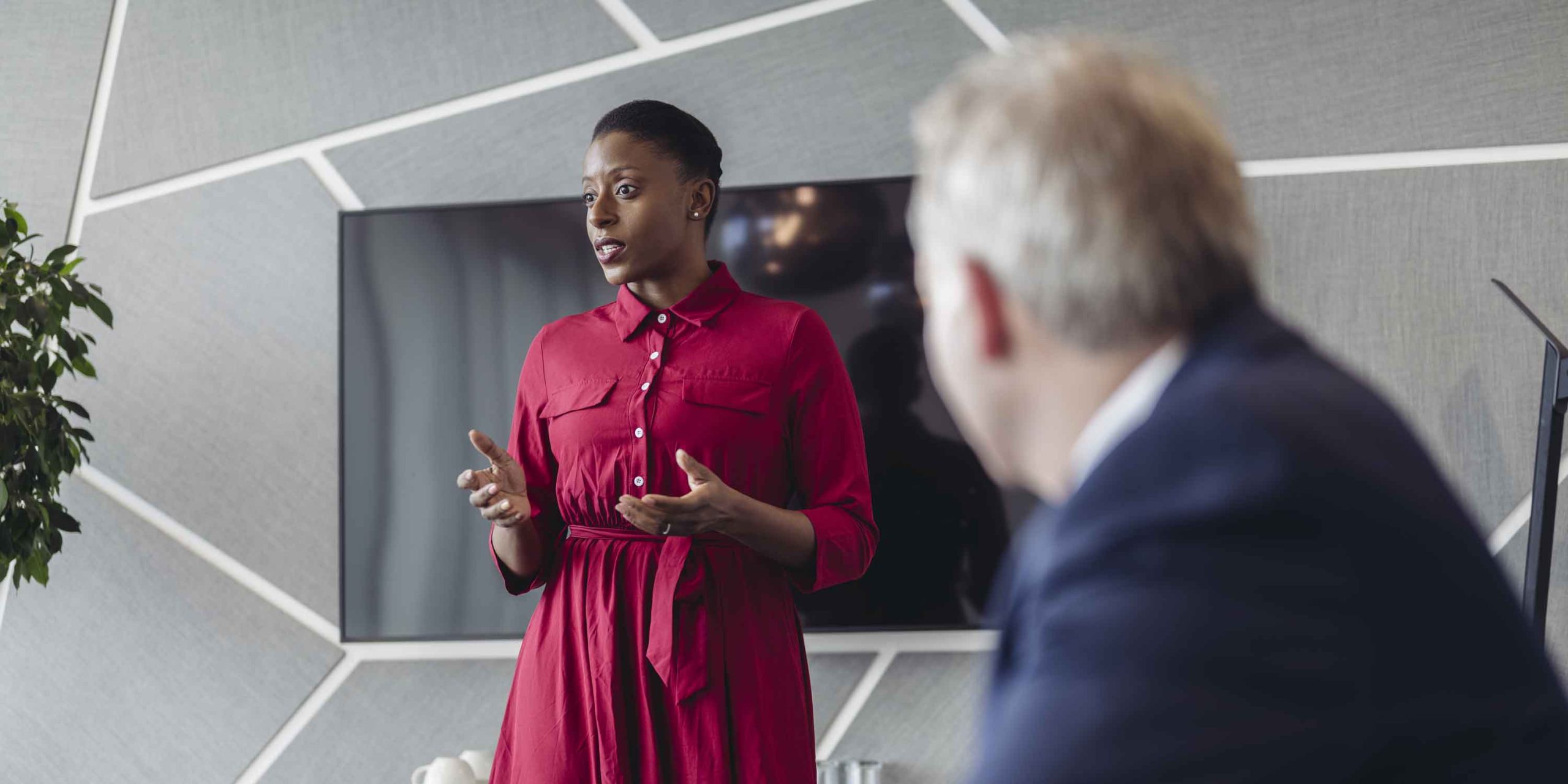 executive standing at head of conference table communicating pitch to colleagues