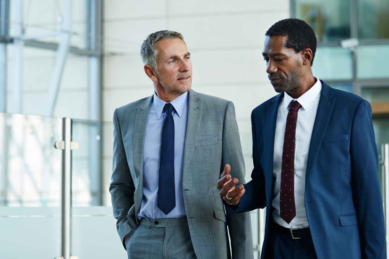 two businessmen walking and talking together in the lobby of an office building