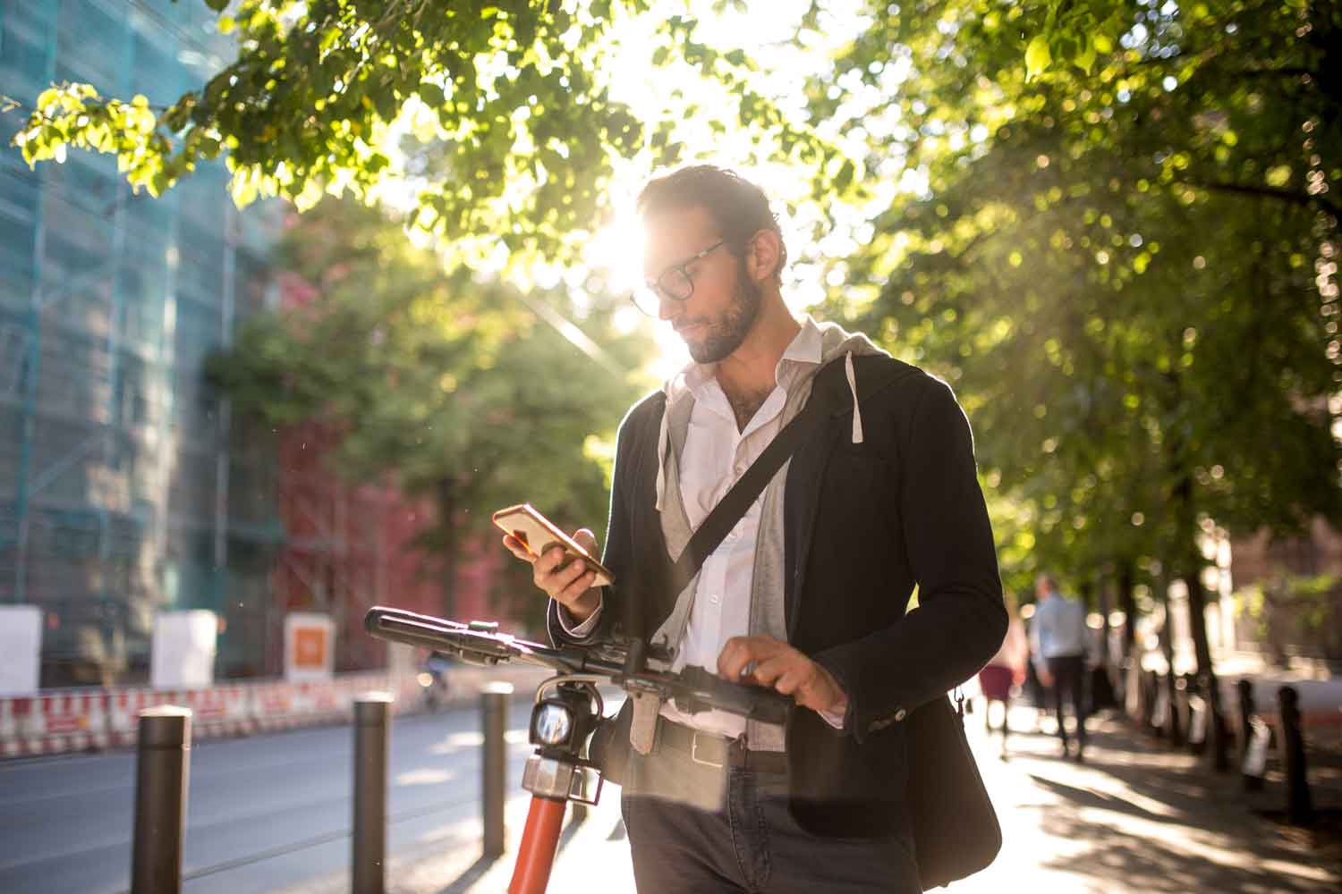 adult male commuting with electric bicycle and looking through his phone