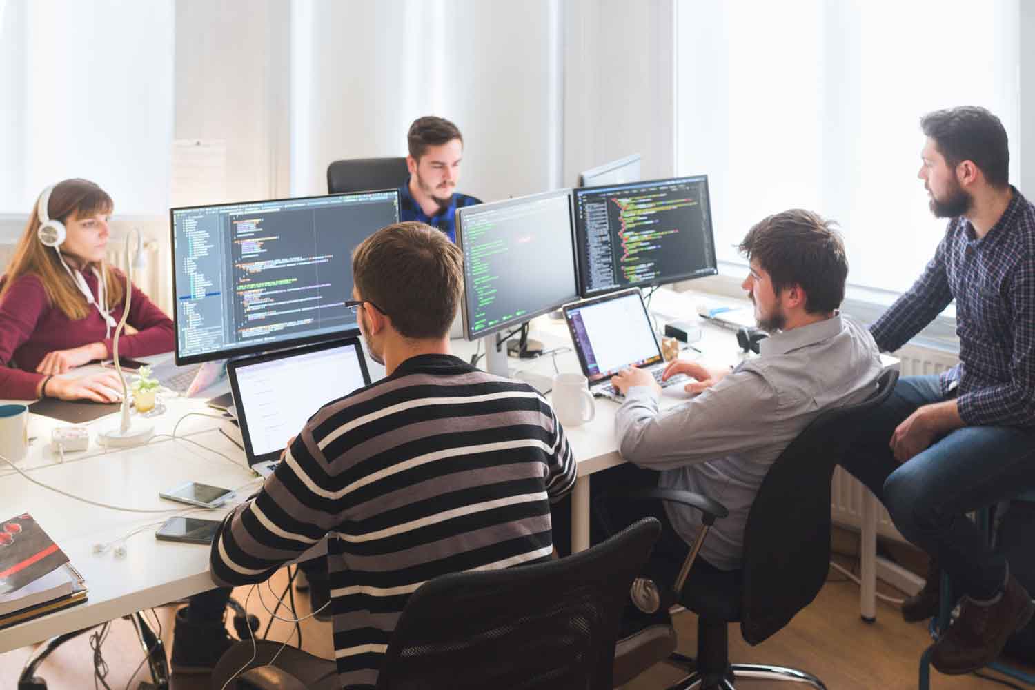 Group of software developers sitting at desktop computers being focused on their work